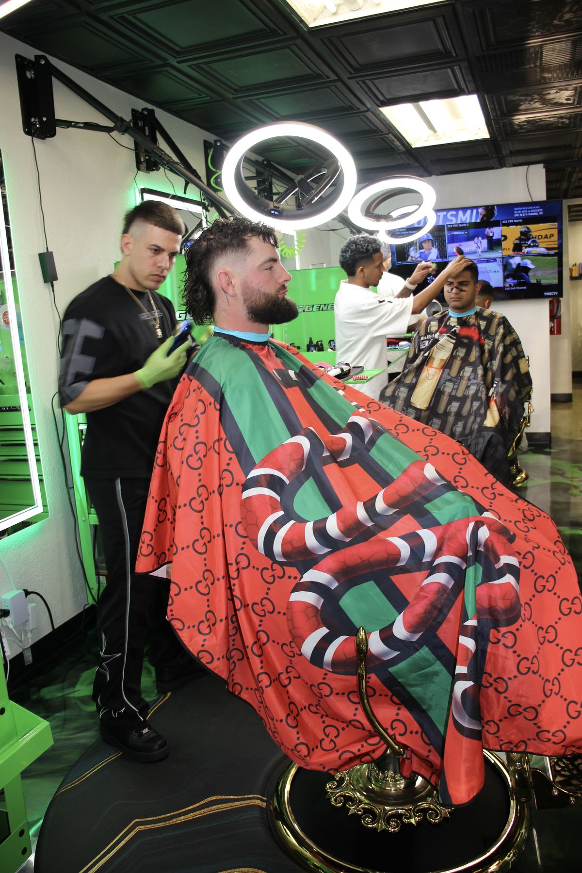 Barber at work with client in Gucci cape